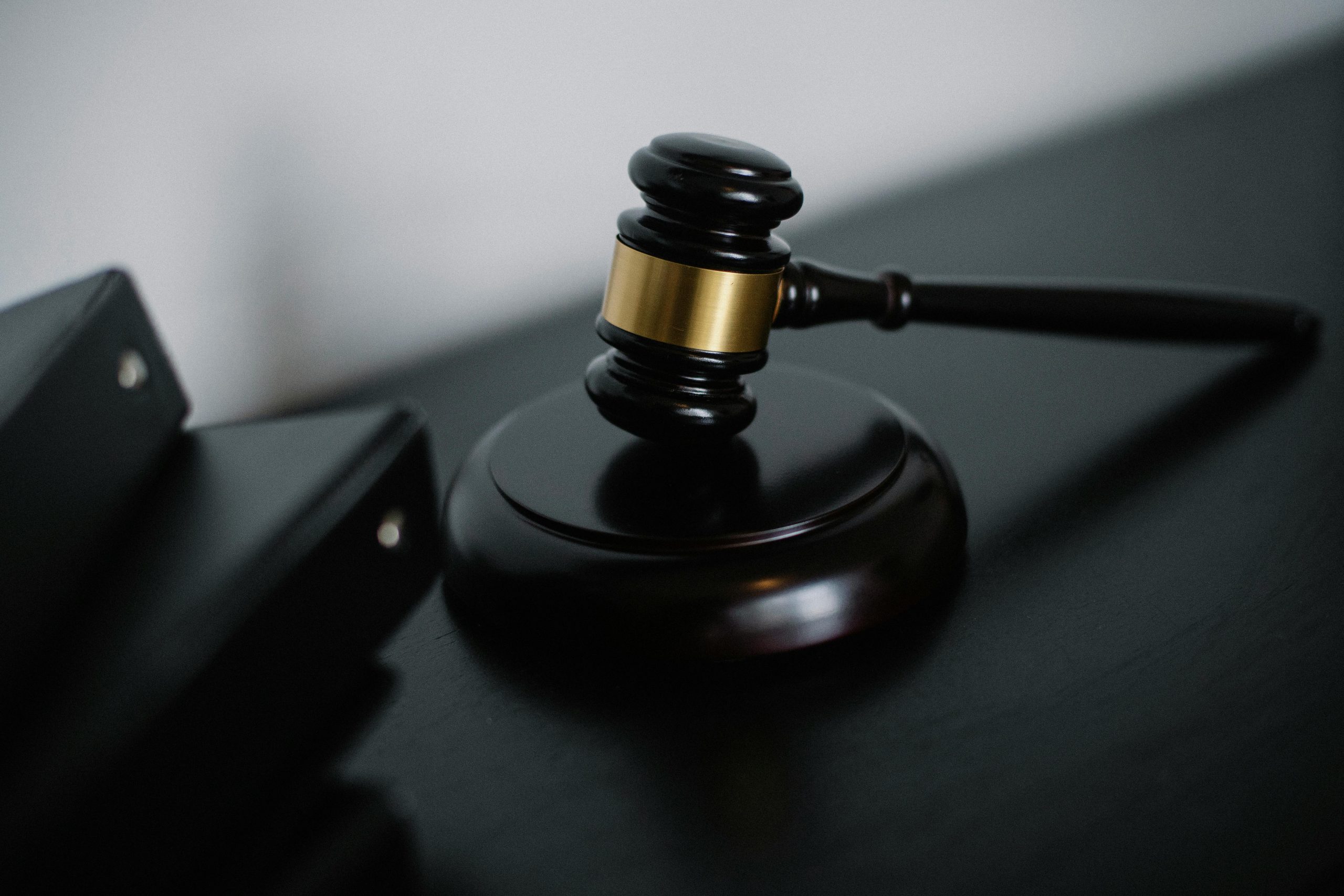 ICRA - A dark wooden gavel rests on its sounding block on a table, with the handle extending to the right. Nearby, three closed black folders marked ICRA are stacked in the foreground, creating a soft focus contrast.